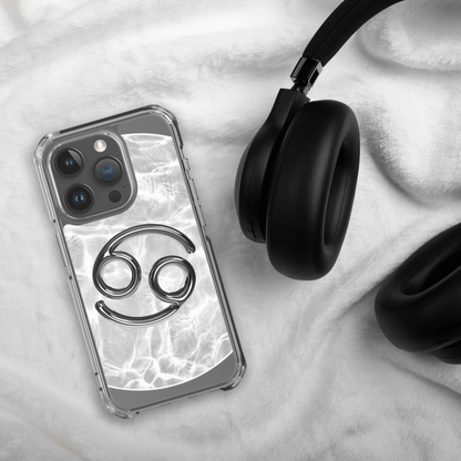 Zodiac Cancer Magsafe clear iPhone case with metallic design on marble background next to black headphones.