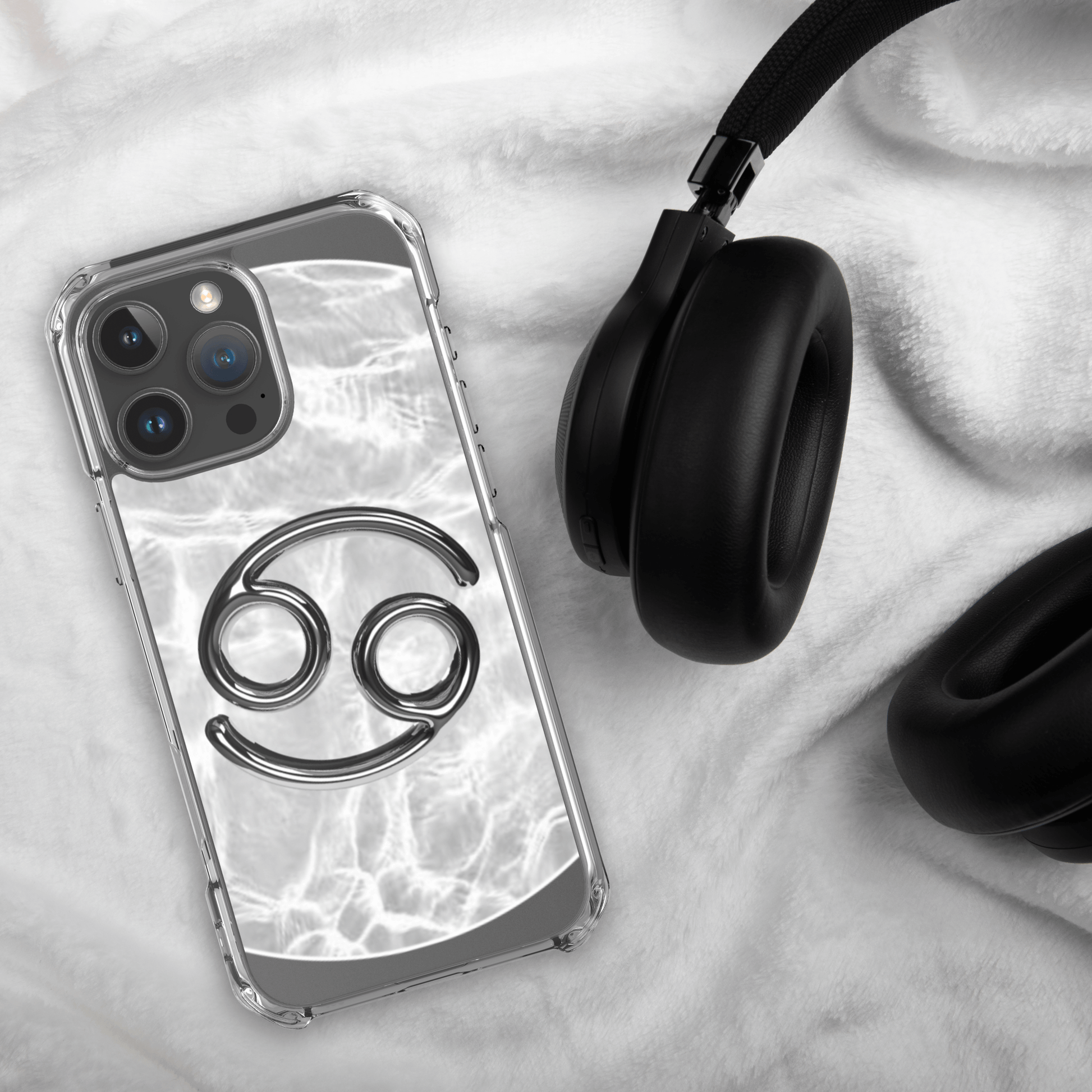 Zodiac Cancer MagSafe clear iPhone case with metallic design on marble background and black headphones.