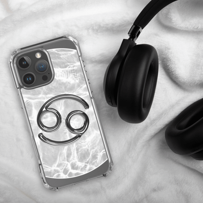 Zodiac Cancer MagSafe clear iPhone case with metallic design on marble background and black headphones.