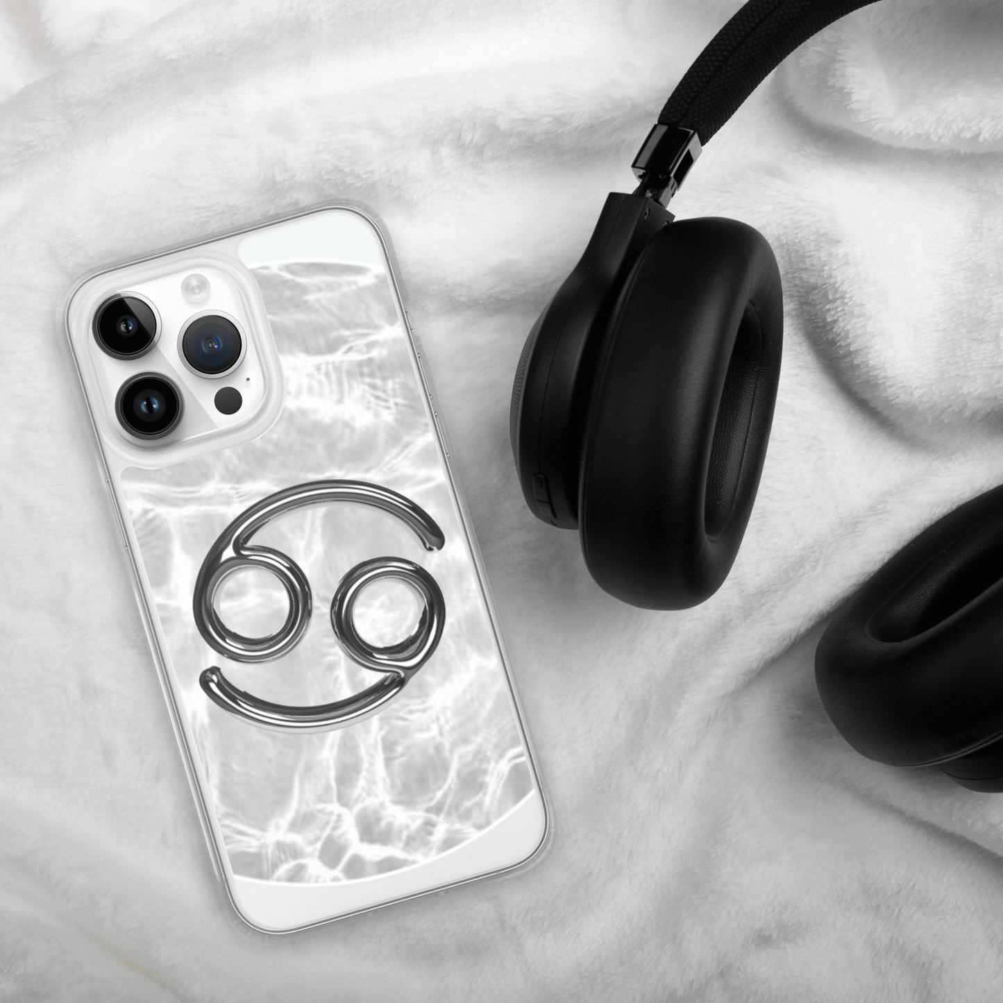 Zodiac Cancer Metallic design clear iPhone case atop soft grey fabric near black headphones.
