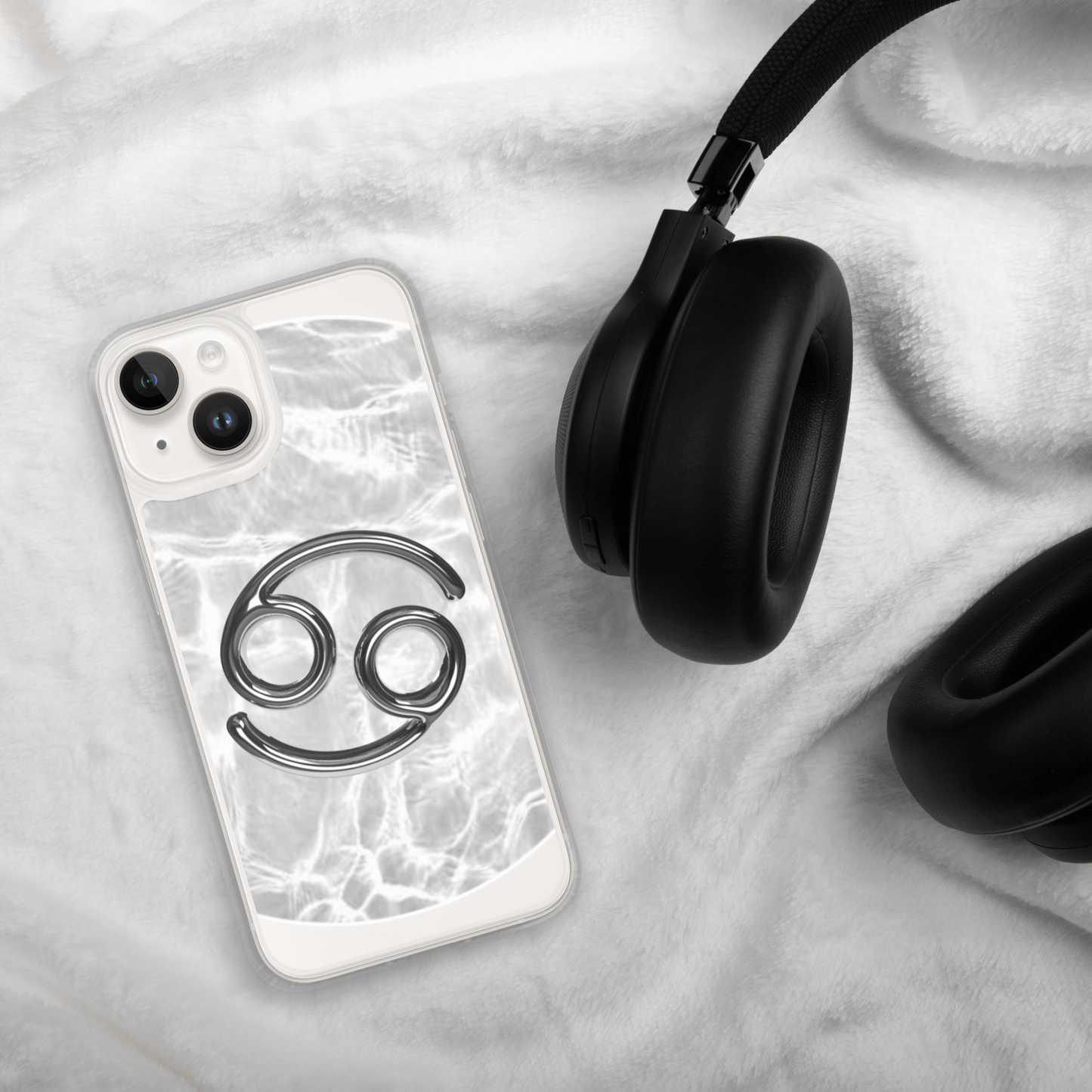 Zodiac Cancer Magsafe clear iPhone case with metallic design on marble background beside black headphones.