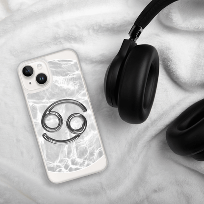 Zodiac Cancer Magsafe clear iPhone case with metallic design on marble background beside black headphones.