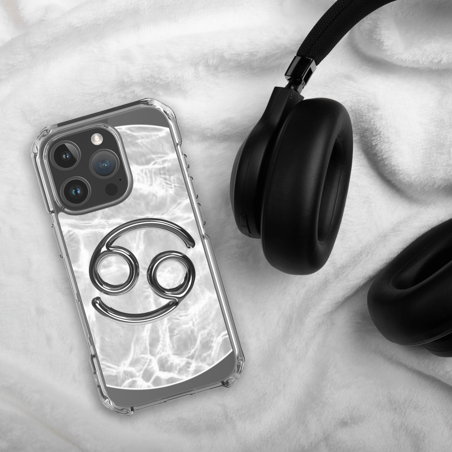 Zodiac Cancer Magsafe clear iPhone case with metallic design on a soft surface, next to black headphones.