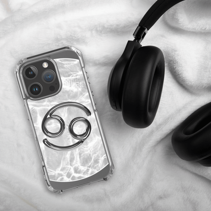 Zodiac Cancer Magsafe clear iPhone case with metallic design on a soft surface, next to black headphones.