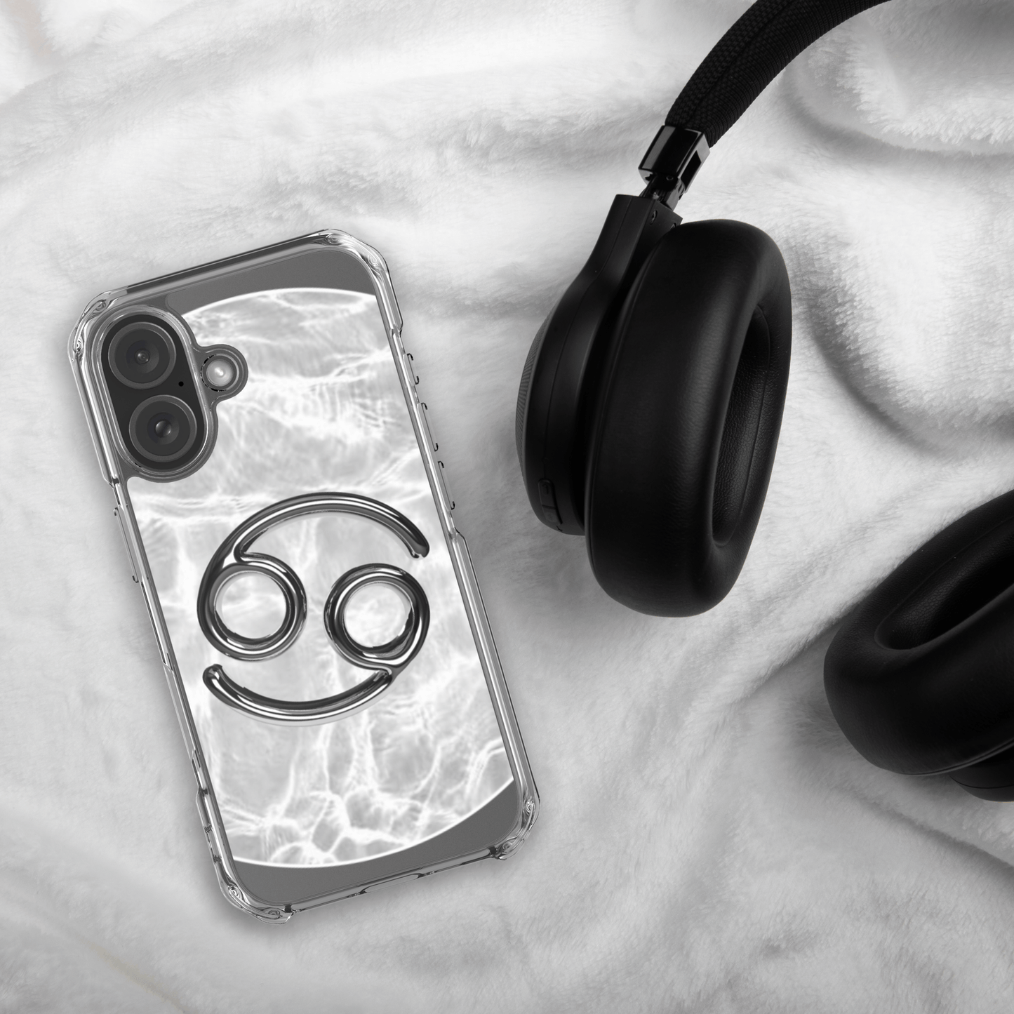 Zodiac Cancer Magsafe Clear iPhone Case with metallic design on marble background next to headphones.