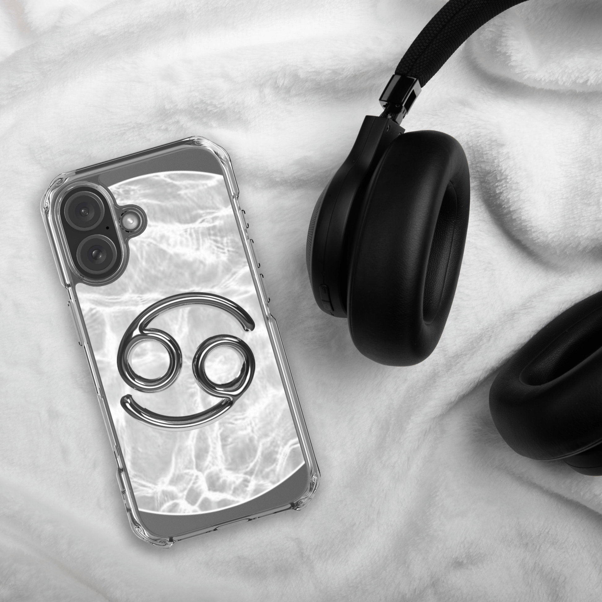 Zodiac Cancer Magsafe Clear iPhone Case with metallic design on marble background next to headphones.
