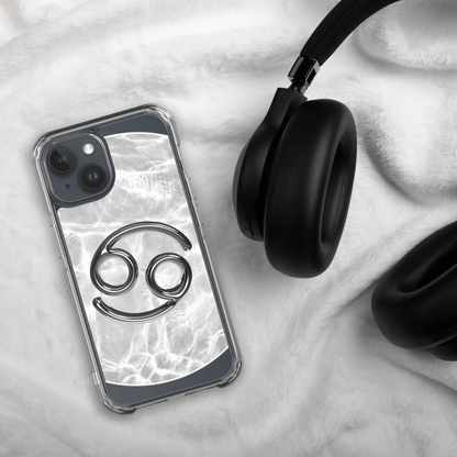 Zodiac Cancer Magsafe clear iPhone case with metallic design, marble background, beside black headphones.