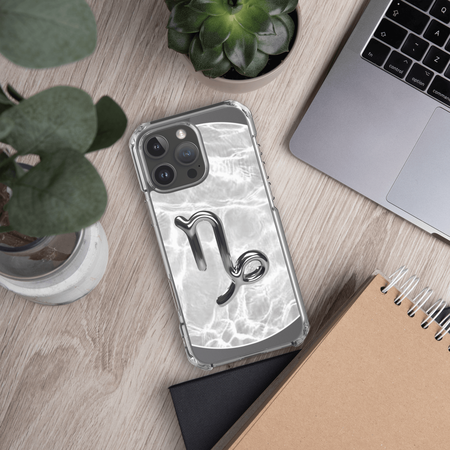 Zodiac Capricorn Magsafe clear iPhone case with marble metallic design on a desk with plants and laptop.