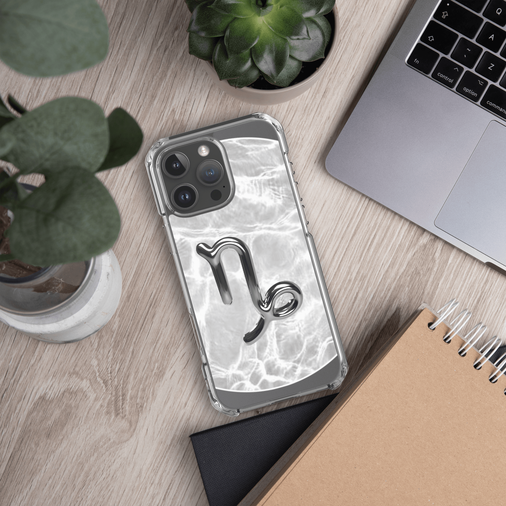 Zodiac Capricorn Magsafe clear iPhone case with marble metallic design on a desk with plants and laptop.