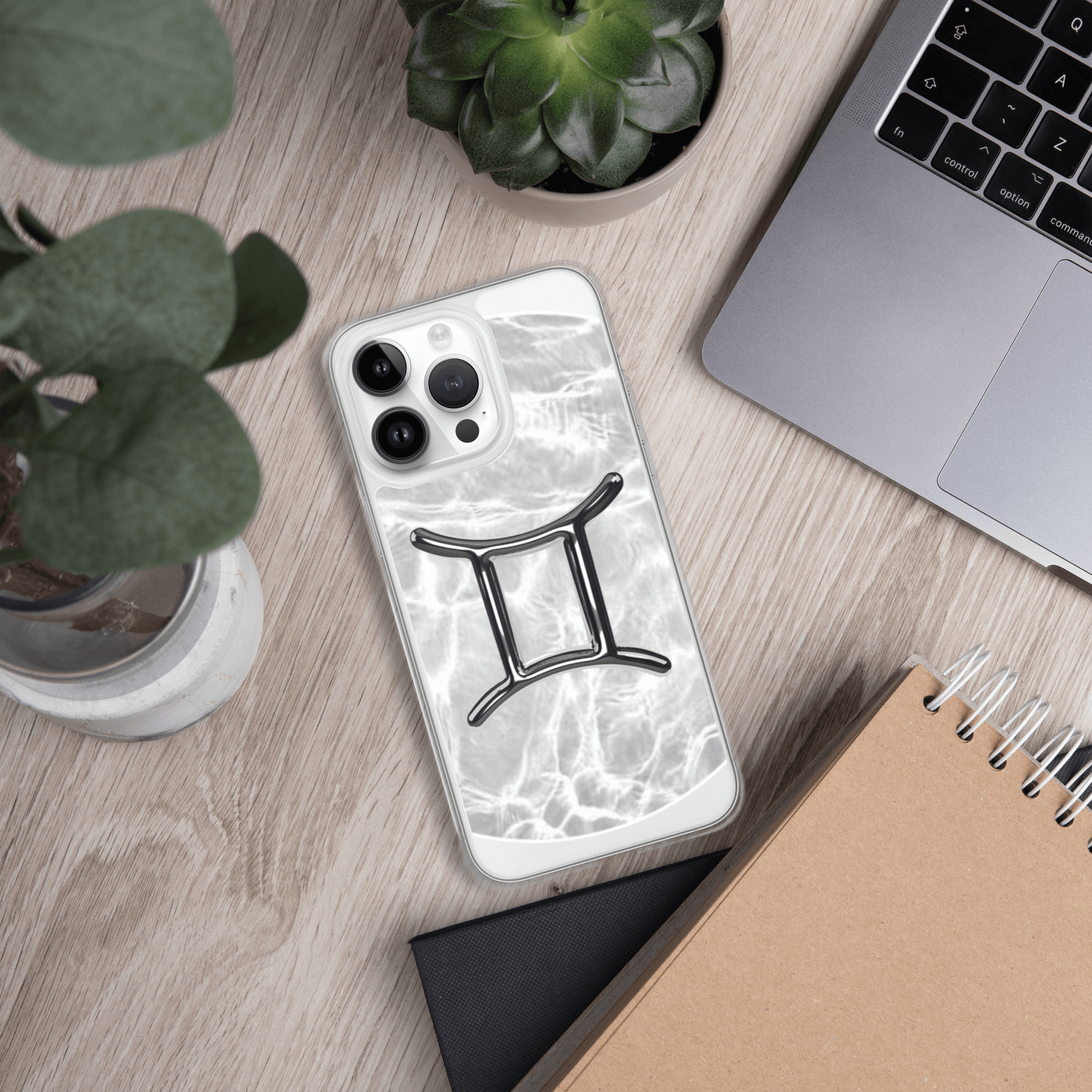 Zodiac Gemini Magsafe clear iPhone case with marble design, stylish and protective on a desk with plants.