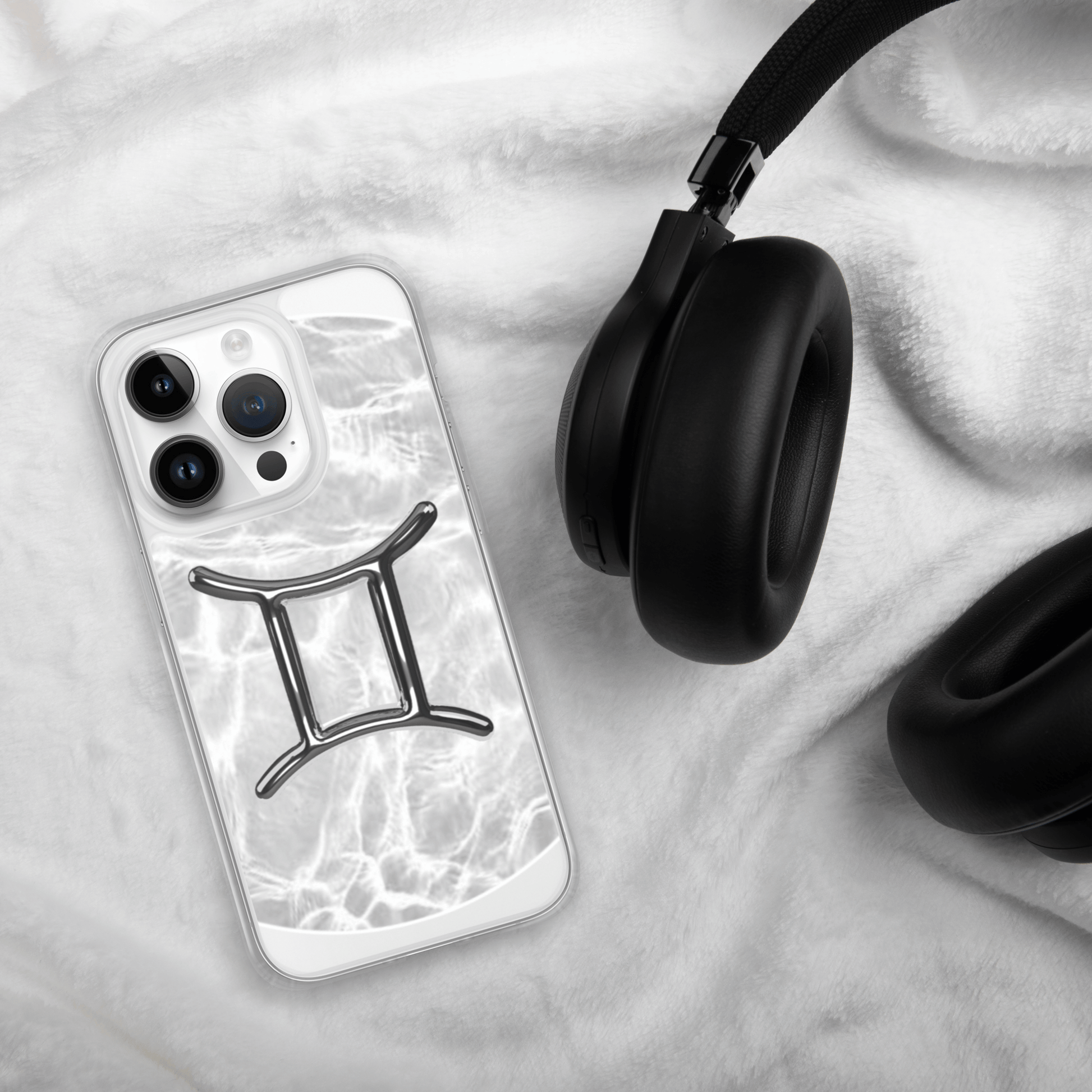 Gemini Magsafe clear iPhone case with marble design next to black headphones on soft fabric.