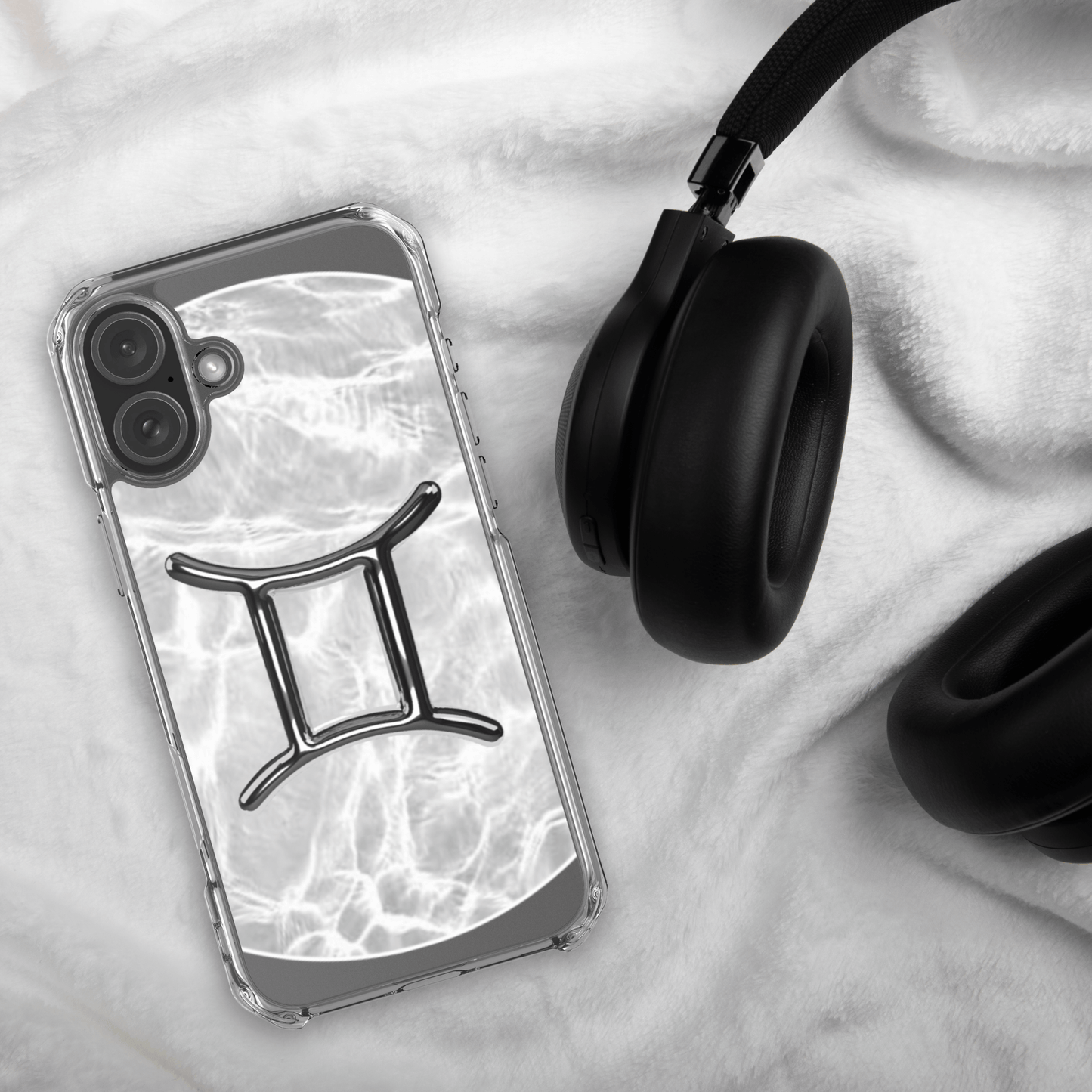 Zodiac Gemini Magsafe clear iPhone case with marble metallic design beside black headphones on a soft surface.