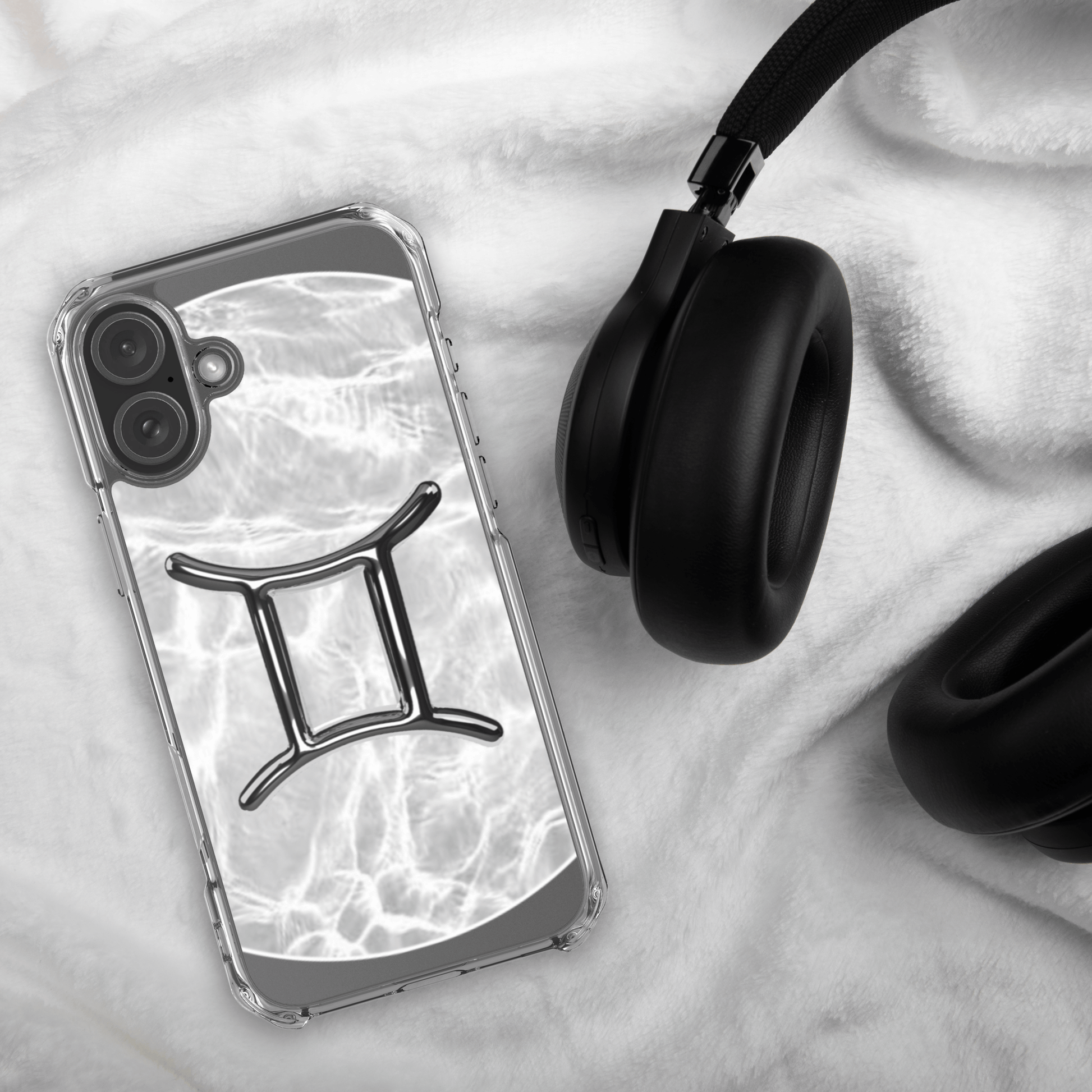 Zodiac Gemini Magsafe clear iPhone case with marble metallic design beside black headphones on a soft surface.