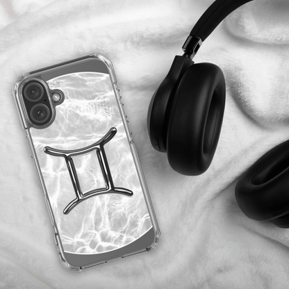 Zodiac Gemini Magsafe clear iPhone case with marble metallic design beside black headphones on a soft surface.