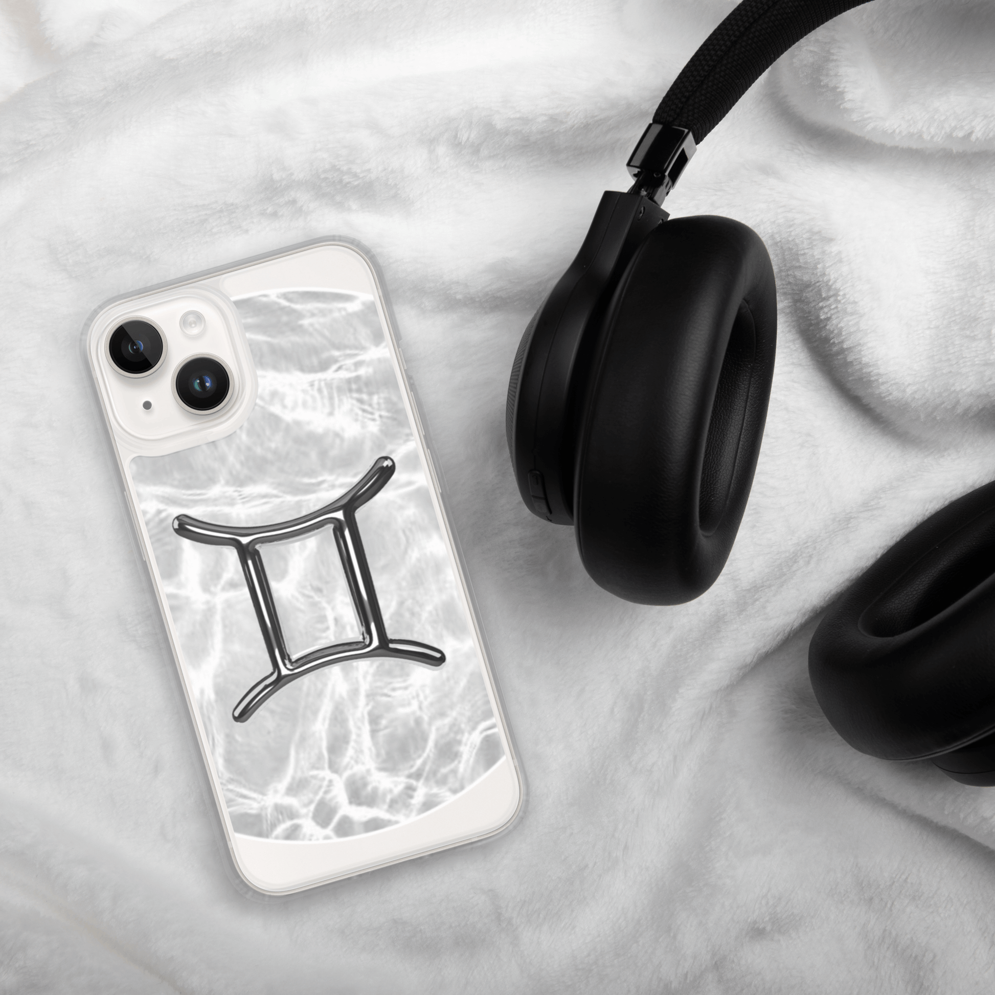 Zodiac Gemini MagSafe iPhone case with metallic design on marble backdrop, next to black headphones.