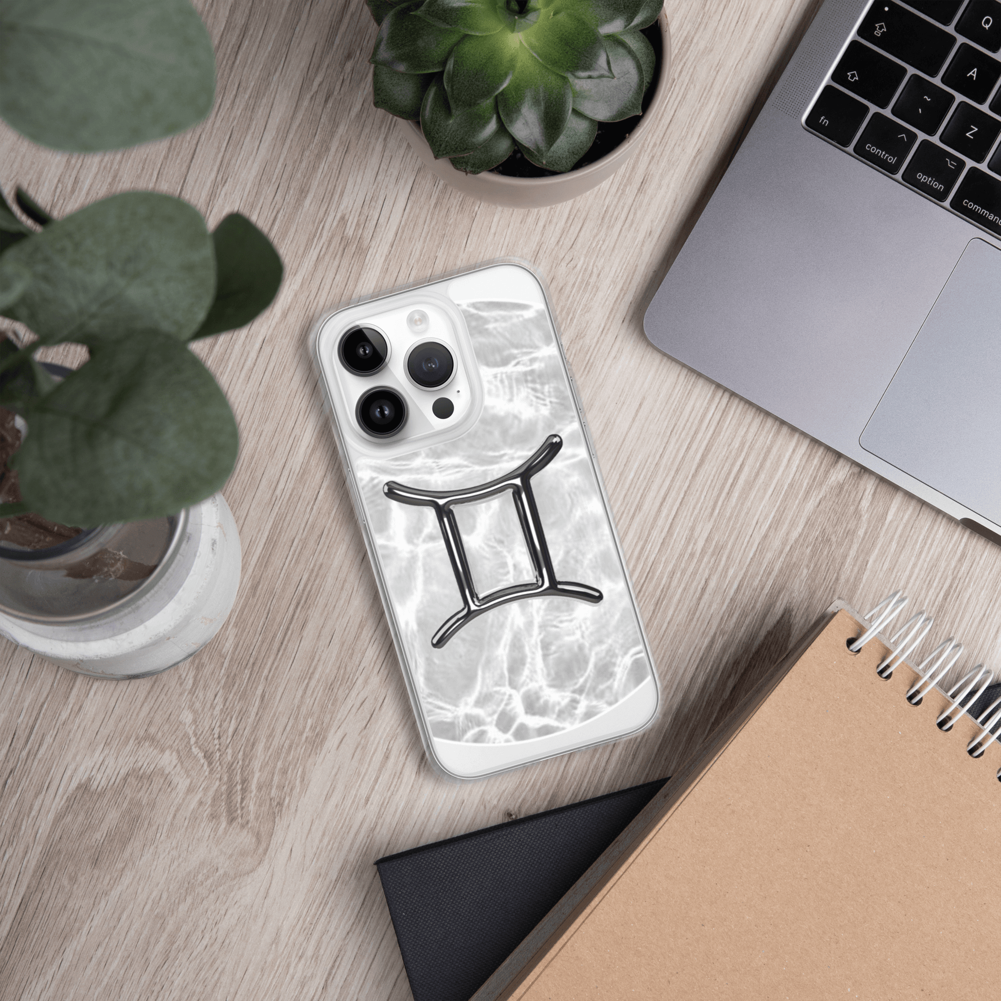 Gemini Magsafe clear iPhone case with marble design on desk, surrounded by plants and a laptop.