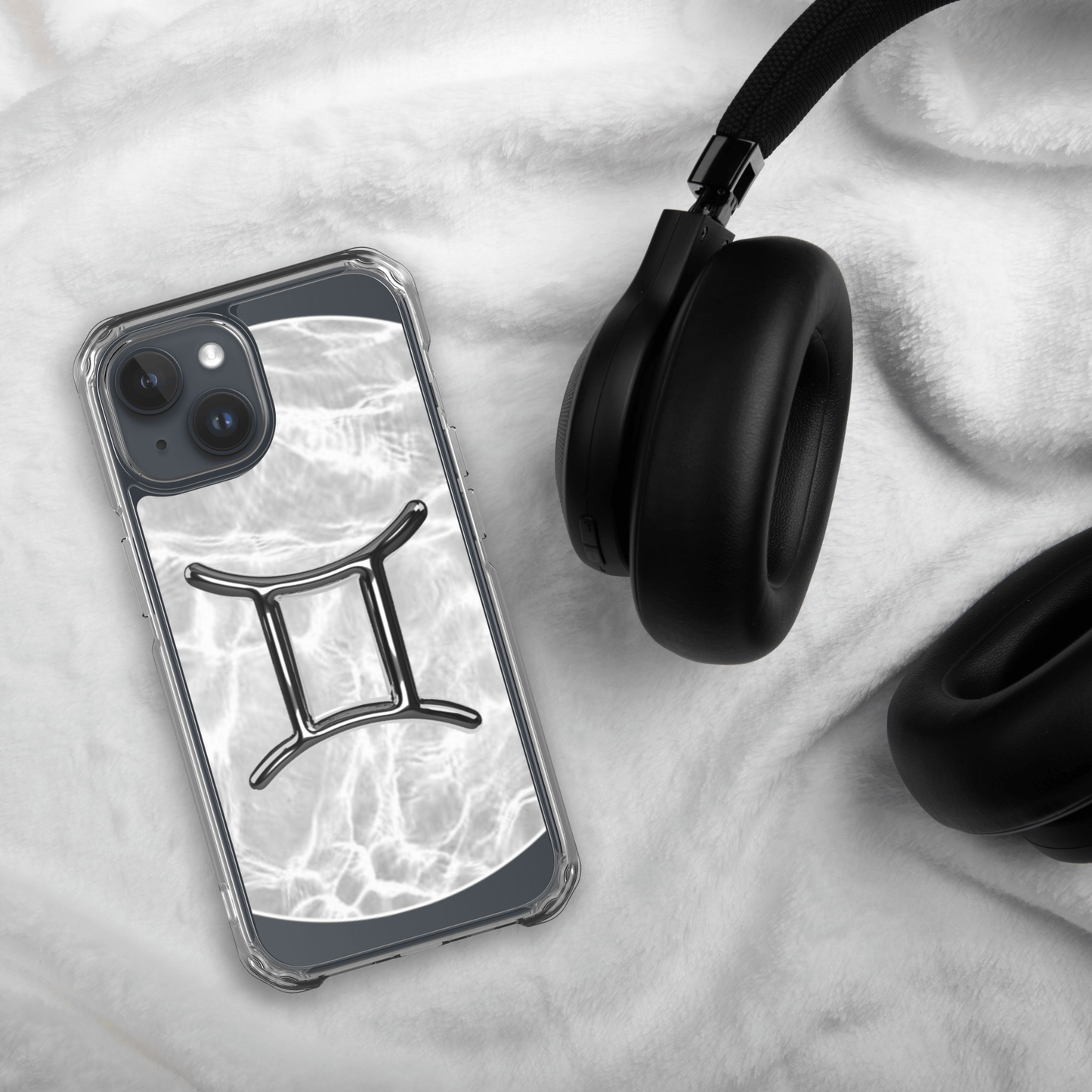 Zodiac Gemini Magsafe Clear iPhone Case with marble design beside black headphones on soft surface.