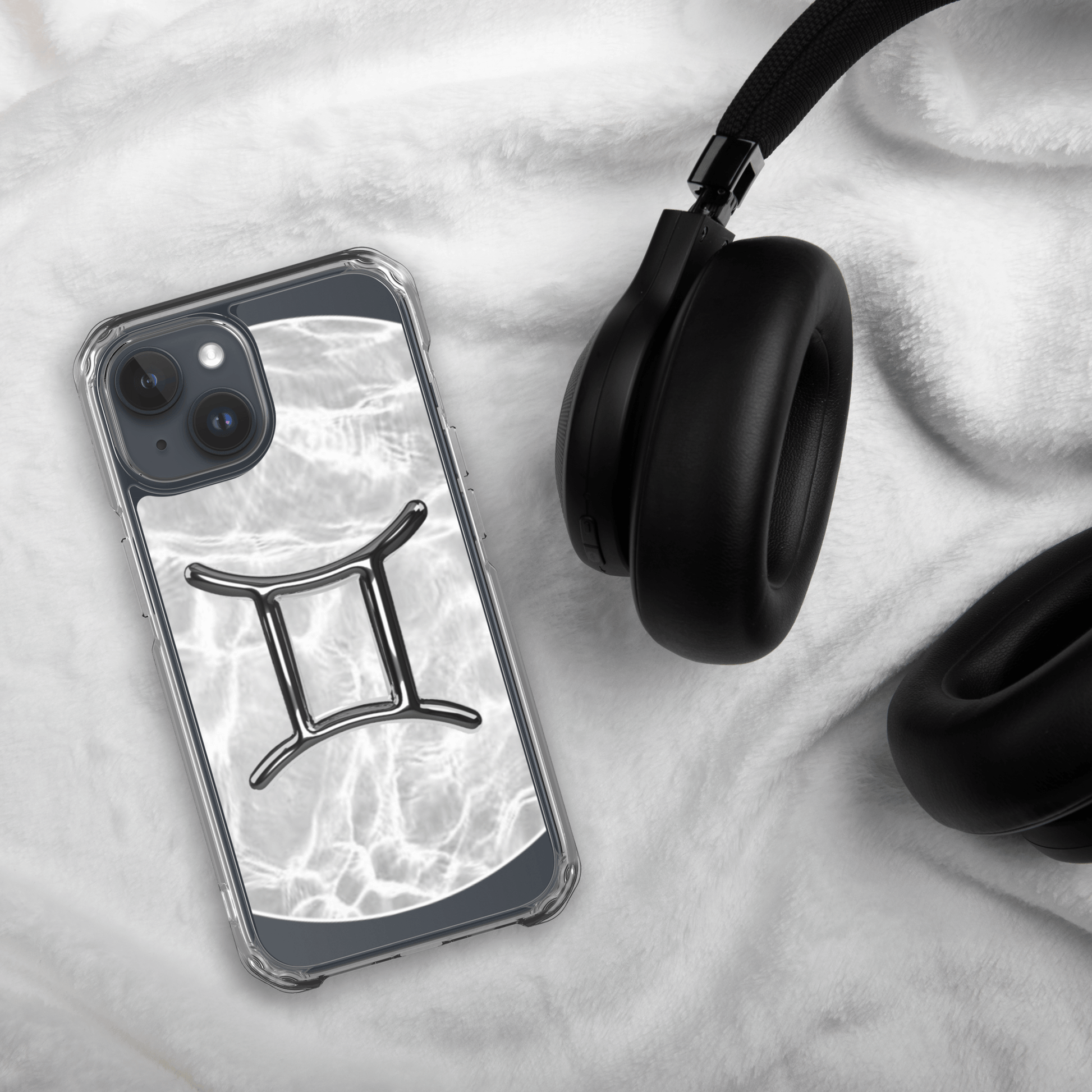 Zodiac Gemini Magsafe Clear iPhone Case with marble design beside black headphones on soft surface.