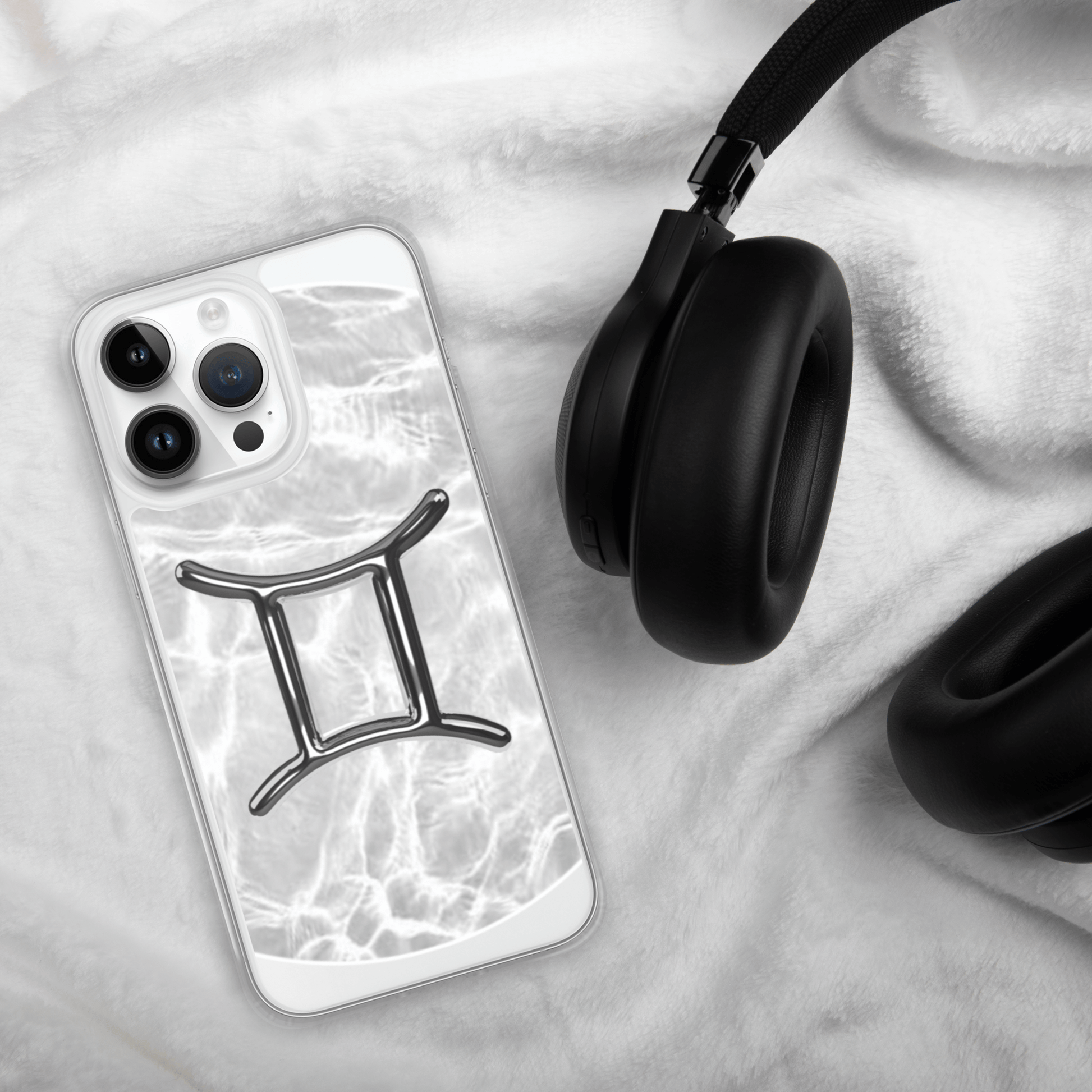 Zodiac Gemini Magsafe clear iPhone case on a white blanket with headphones, featuring a metallic design.