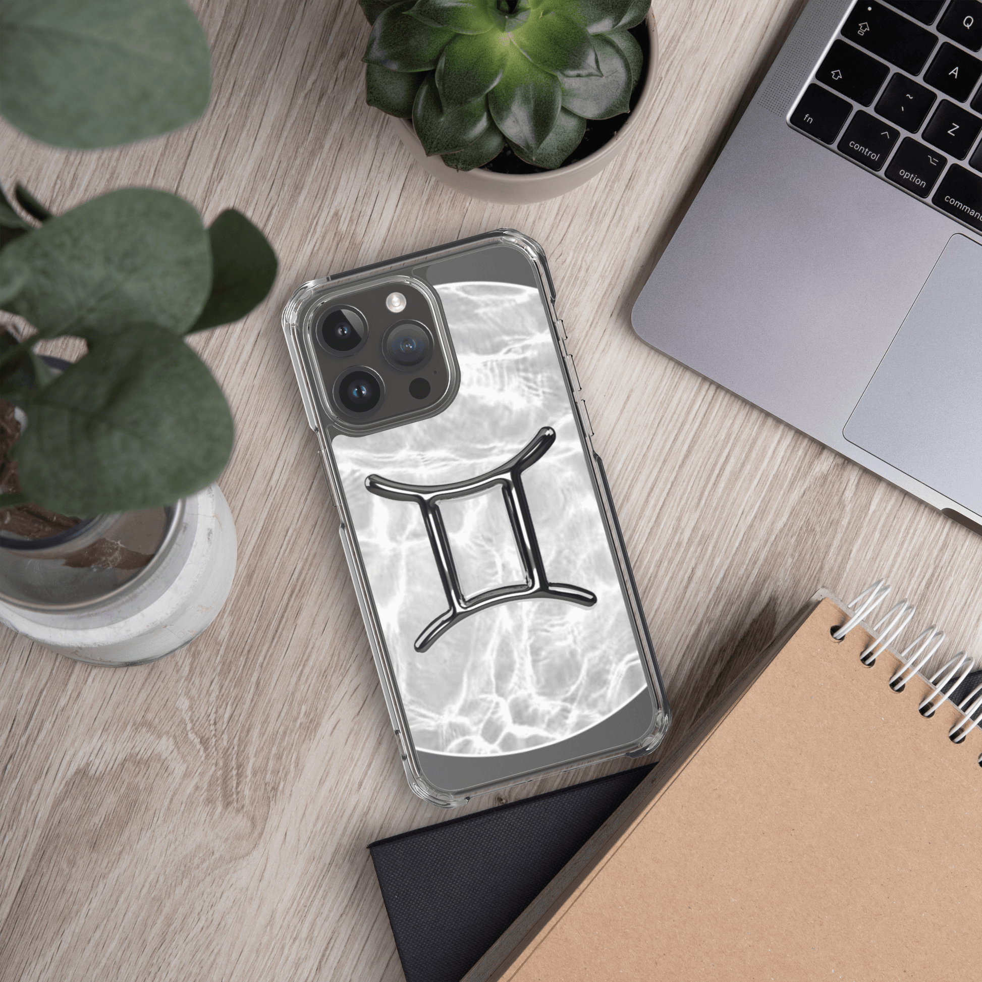 Zodiac Gemini Magsafe clear iPhone case with marble design on a desk, surrounded by plants and a laptop.