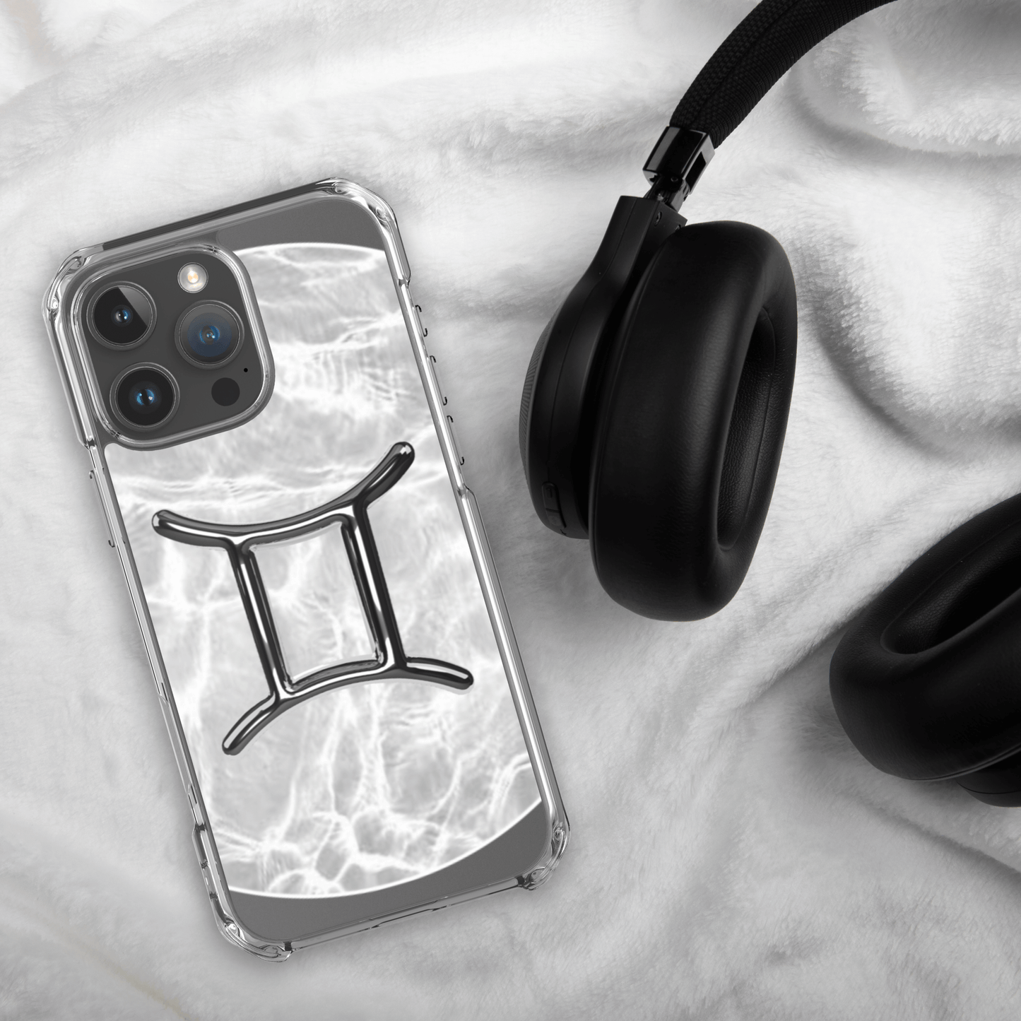 Zodiac Gemini Magsafe clear iPhone case with marble design and headphone on white fabric background.