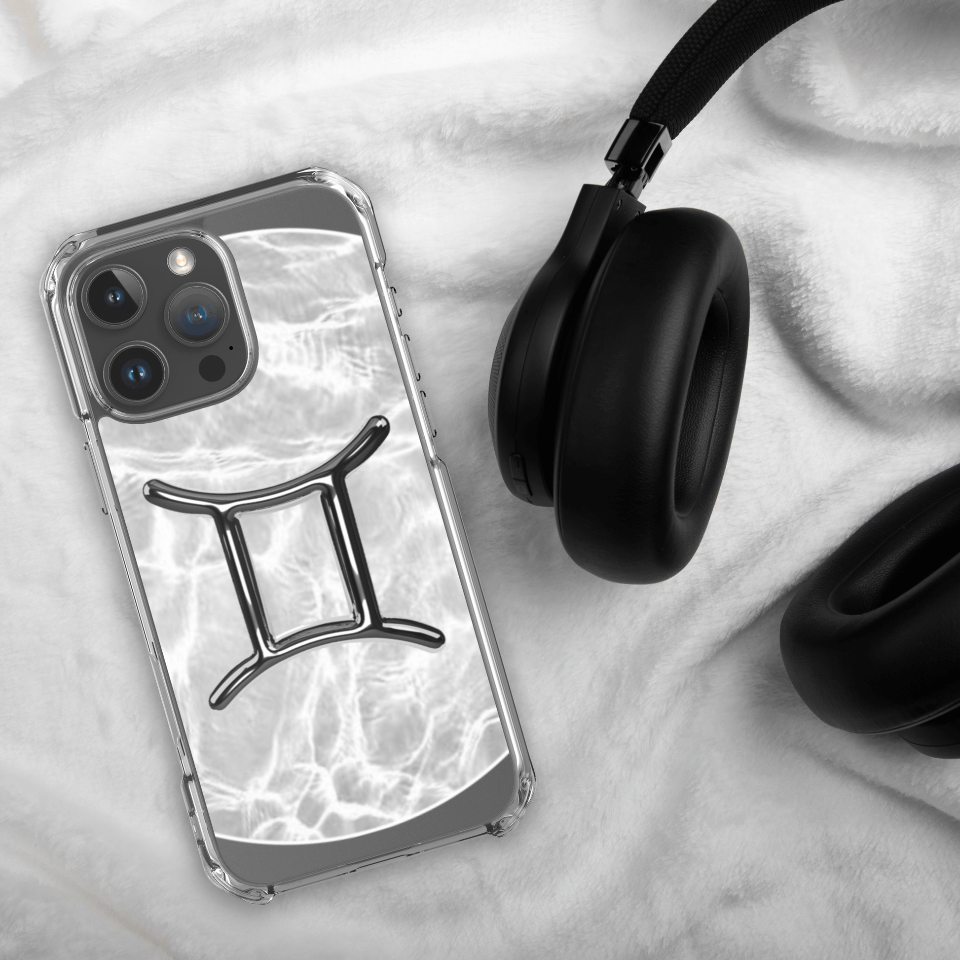 Zodiac Gemini Magsafe clear iPhone case with marble design and headphone on white fabric background.