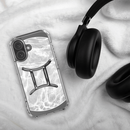 Zodiac Gemini MagSafe clear iPhone case in marble design next to black headphones on soft fabric background.