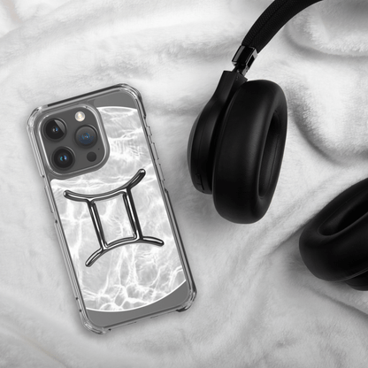 Zodiac Gemini MagSafe clear iPhone case with marble metallic design beside black headphones on soft surface.
