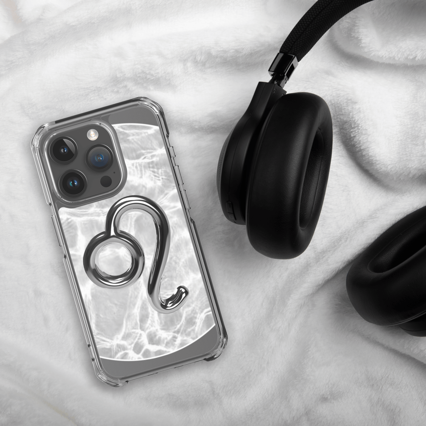 Zodiac Leo Magsafe clear iPhone case with metallic design on soft background next to black headphones.