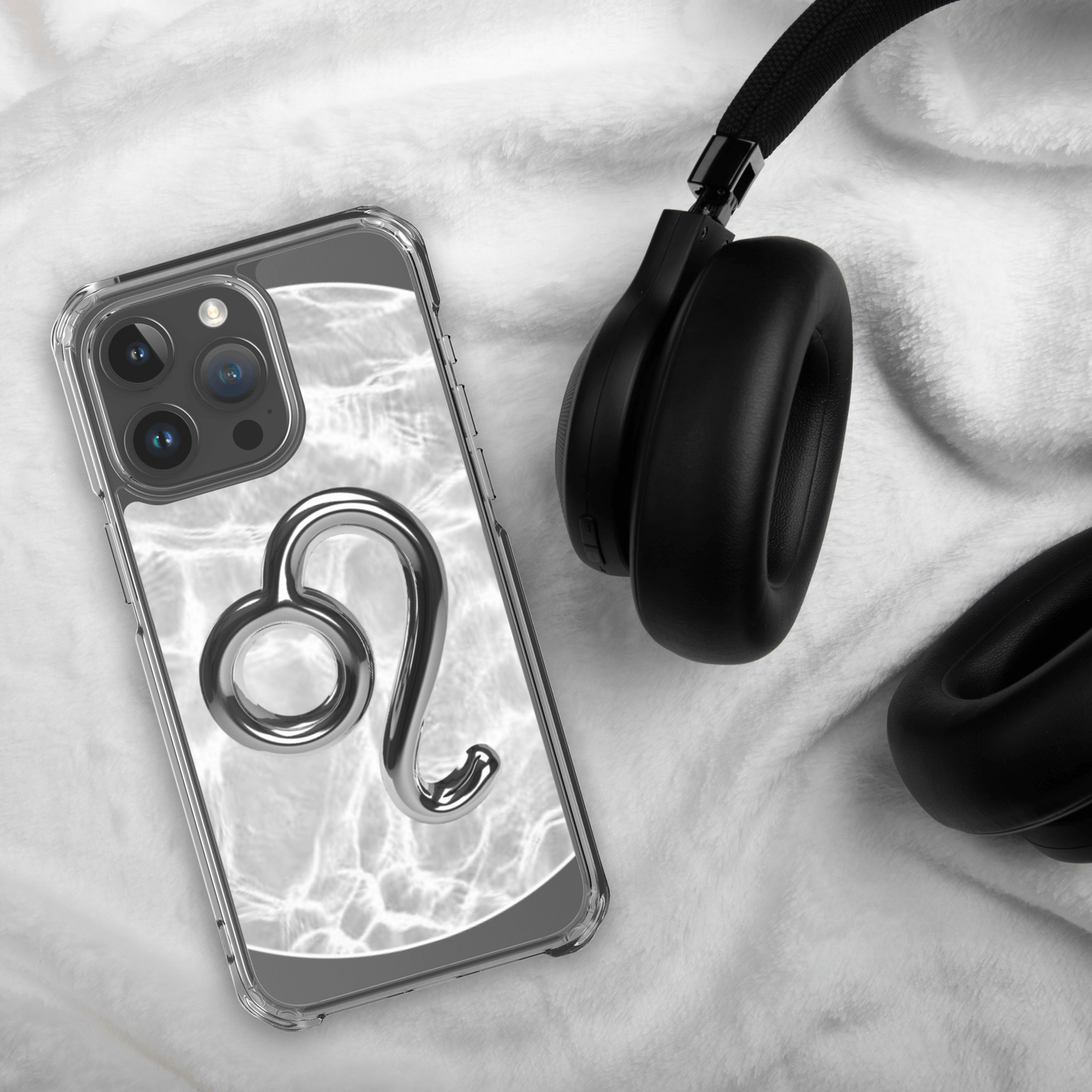 Zodiac Leo Magsafe clear iPhone case with metallic design on a cozy background next to headphones.