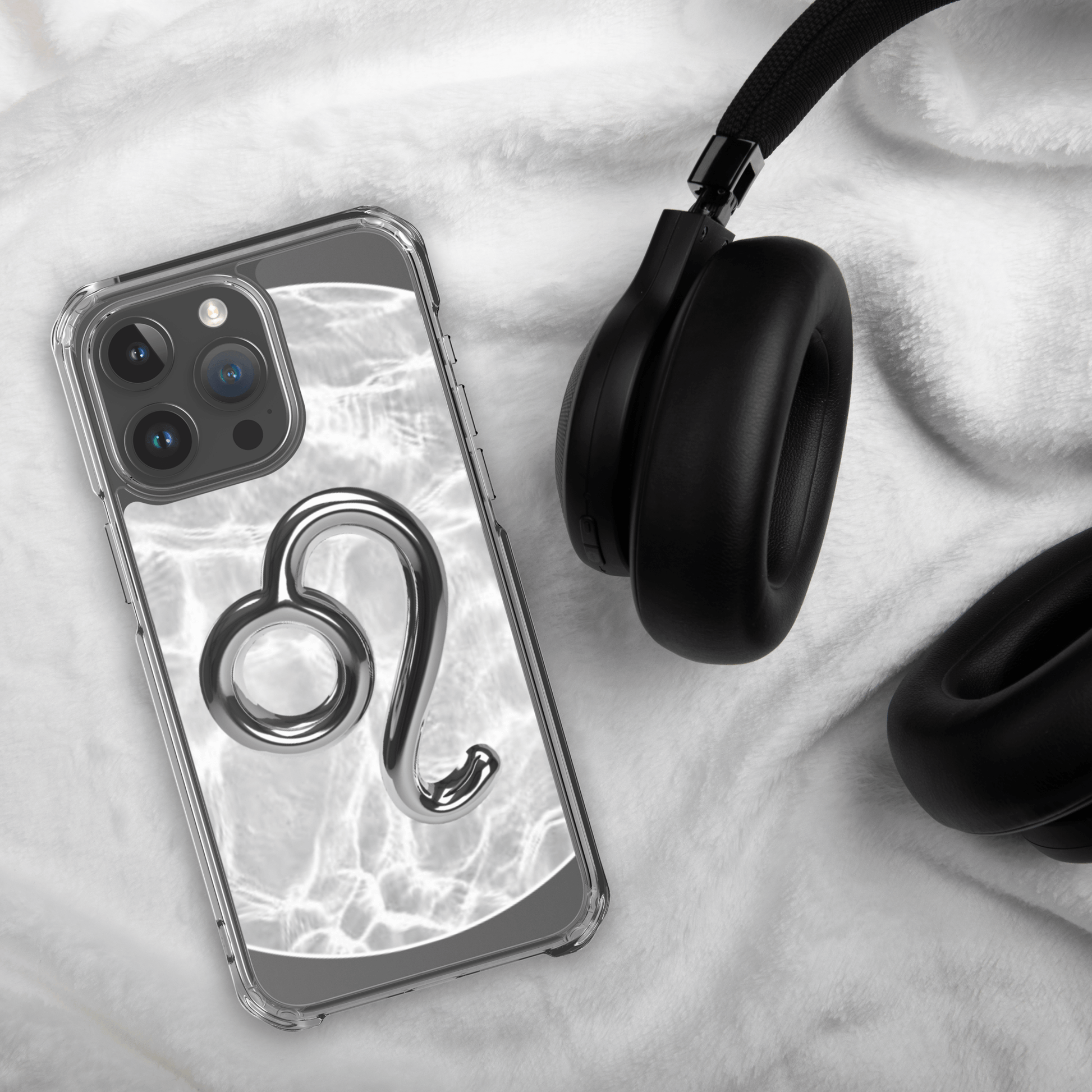 Zodiac Leo Magsafe clear iPhone case with metallic design on a cozy background next to headphones.