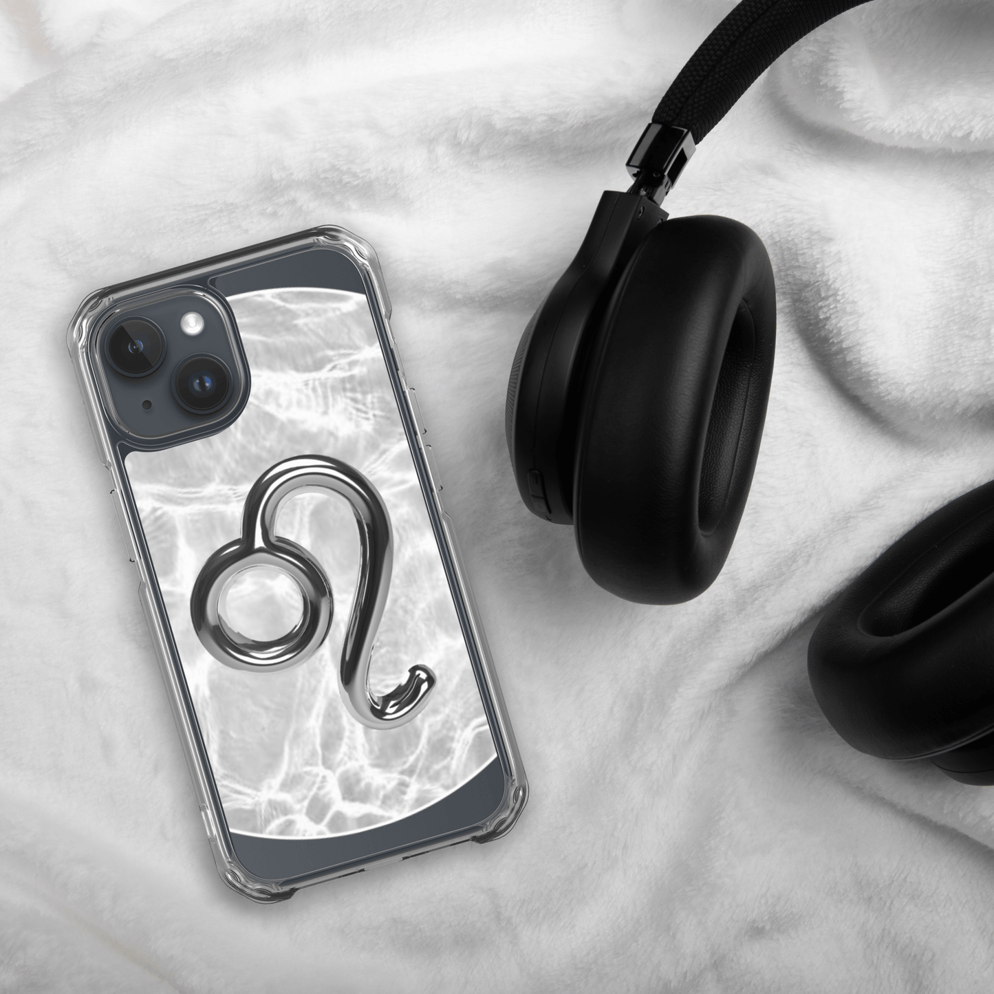 Zodiac Leo Magsafe clear iPhone case with marble design, next to black headphones on soft fabric.