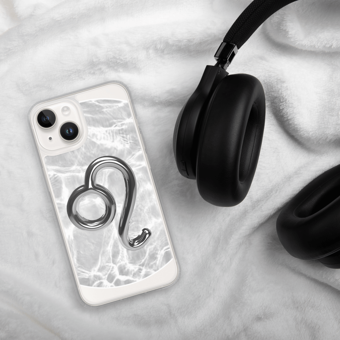 Zodiac Leo Magsafe iPhone case with metallic design on marble background next to black headphones.