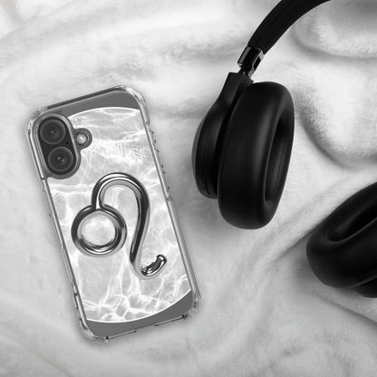 Zodiac Leo Magsafe clear iPhone case with metallic design on a soft surface beside black headphones.