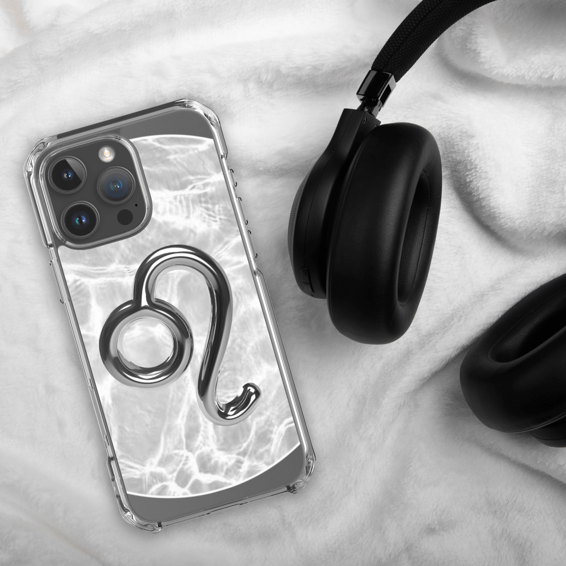 Zodiac Leo Magsafe clear iPhone case with metallic design on marble background, resting next to black headphones.