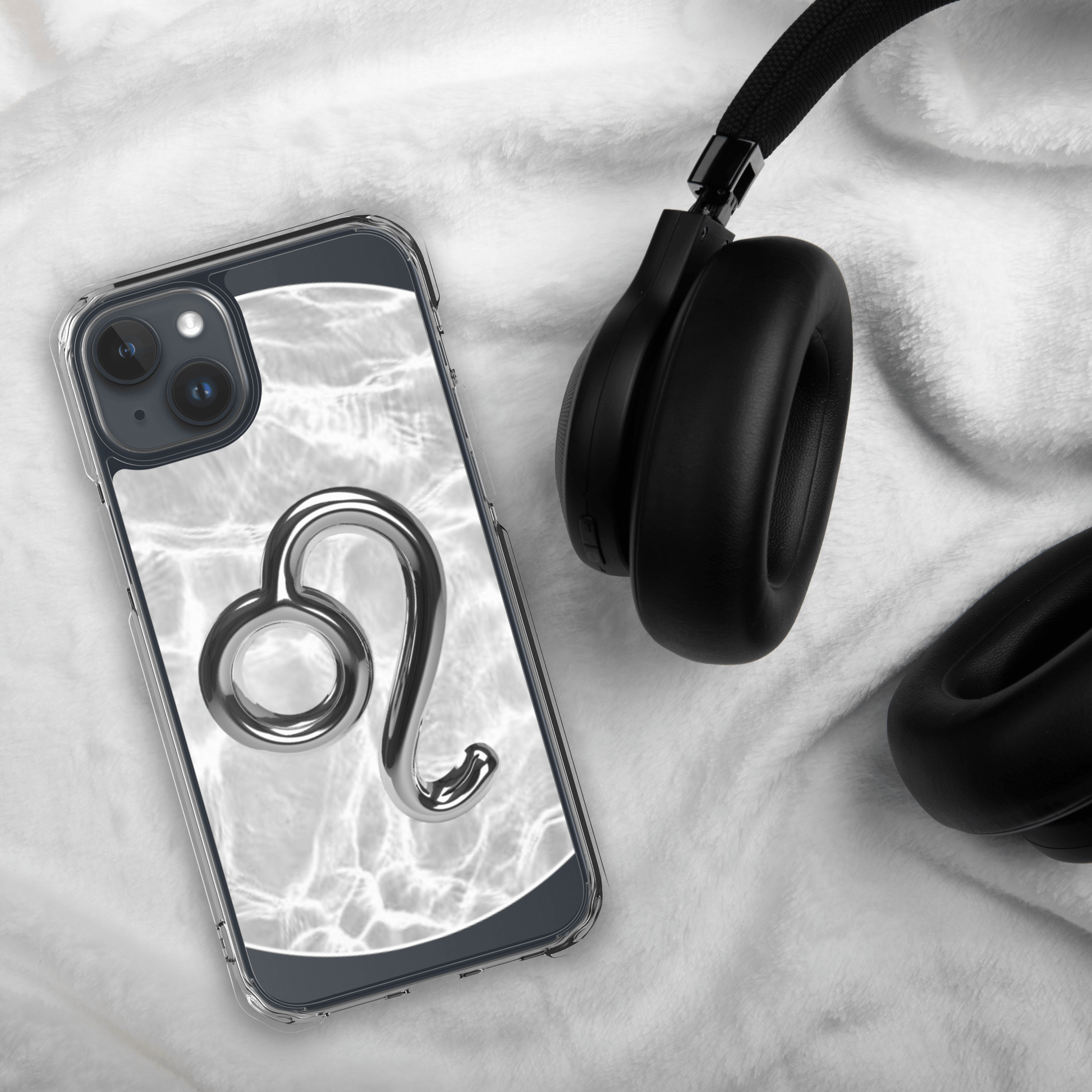 Zodiac Leo Magsafe clear iPhone case with metallic design on marble background, beside black headphones.