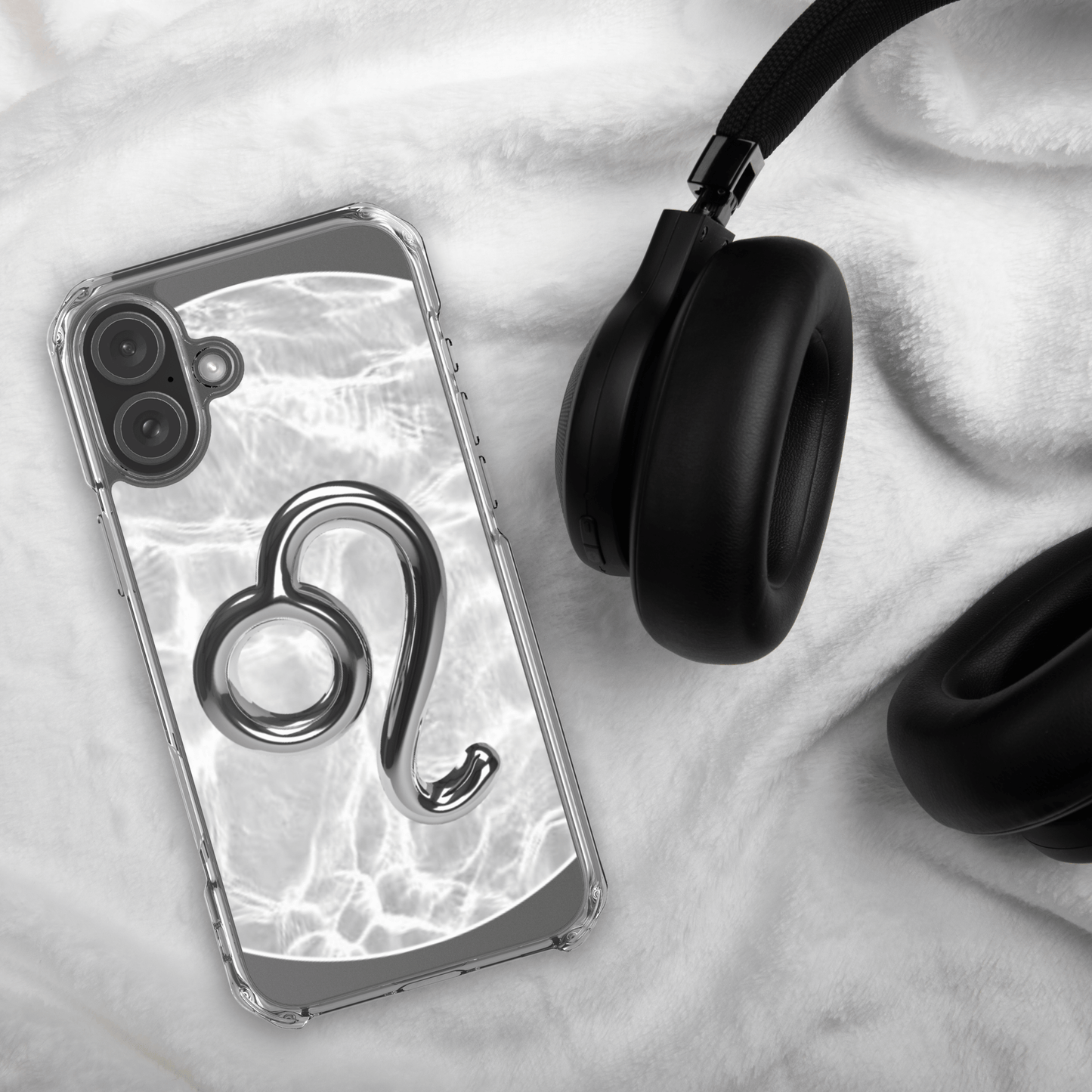 Zodiac Leo Magsafe Clear iPhone Case with metallic design on marble background next to black headphones.