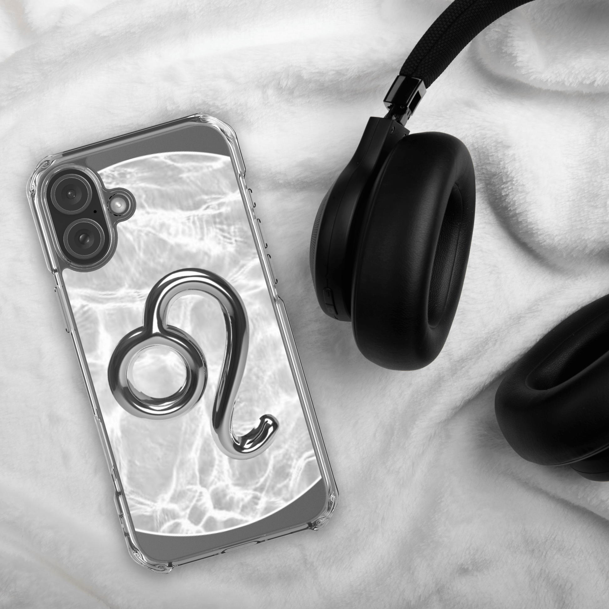 Zodiac Leo Magsafe Clear iPhone Case with metallic design on marble background next to black headphones.