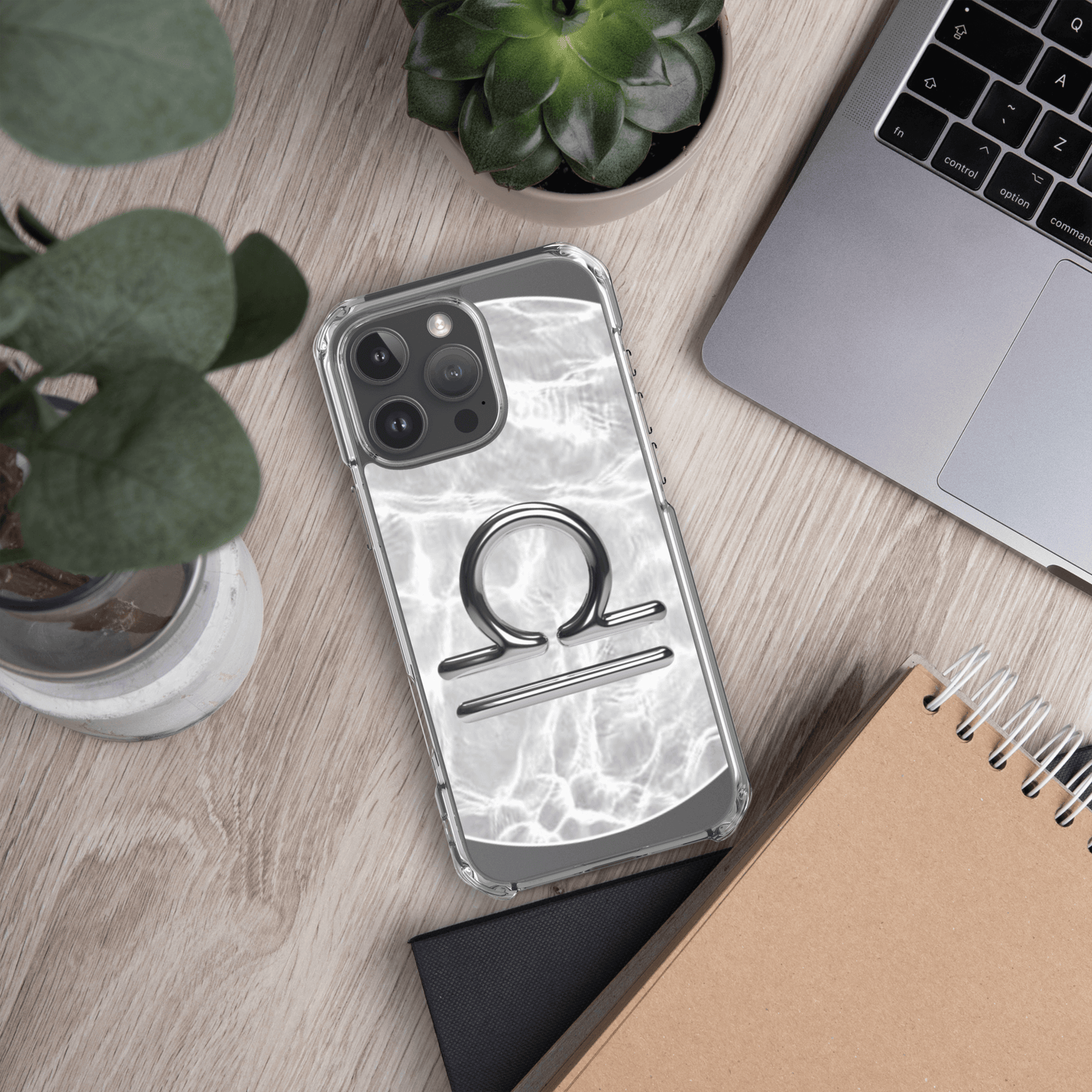 Libra Magsafe clear iPhone case with marble design on a wooden desk with plants and a laptop.