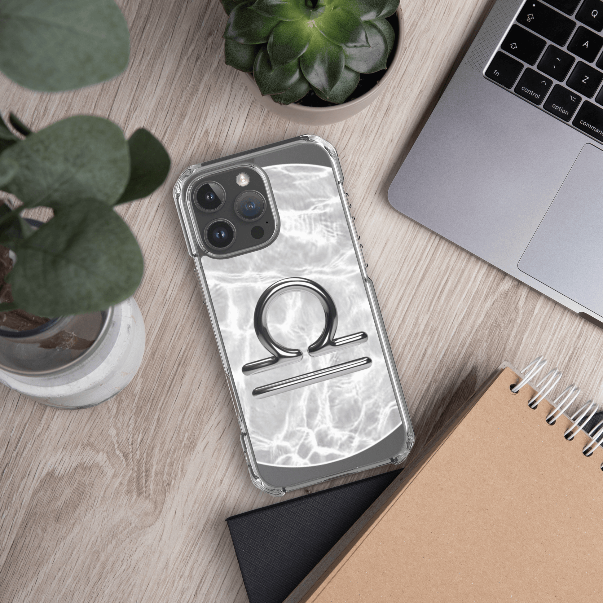 Libra Magsafe clear iPhone case with marble design on a wooden desk with plants and a laptop.