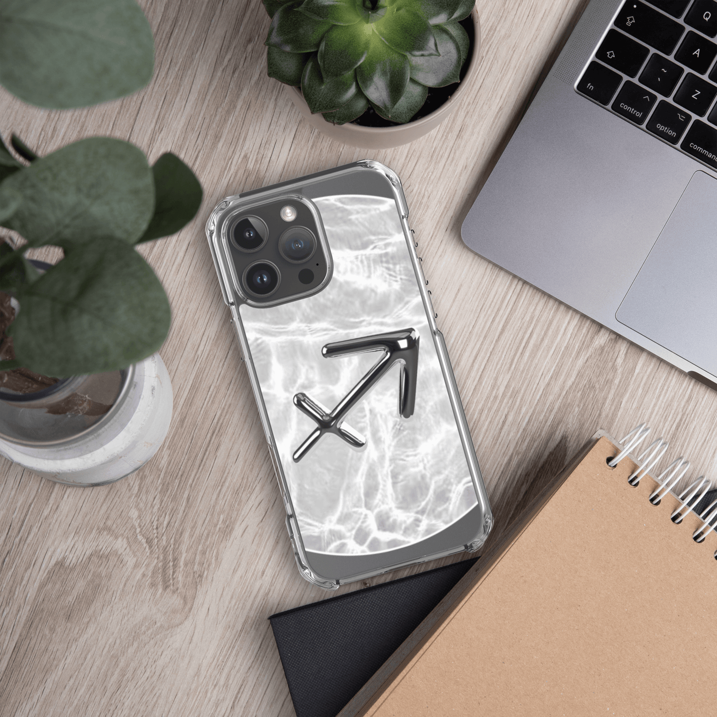 Zodiac Sagittarius MagSafe clear iPhone case with metallic design on a wooden desk surrounded by plants and notebook.