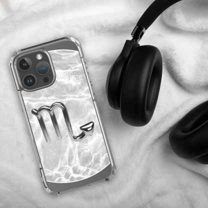Zodiac Scorpio Magsafe clear iPhone case with metallic design, resting beside black headphones on a white cloth.