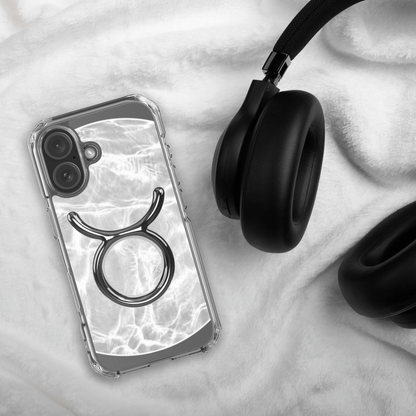 Zodiac Taurus MagSafe clear iPhone case with metallic design on a soft background next to black headphones.