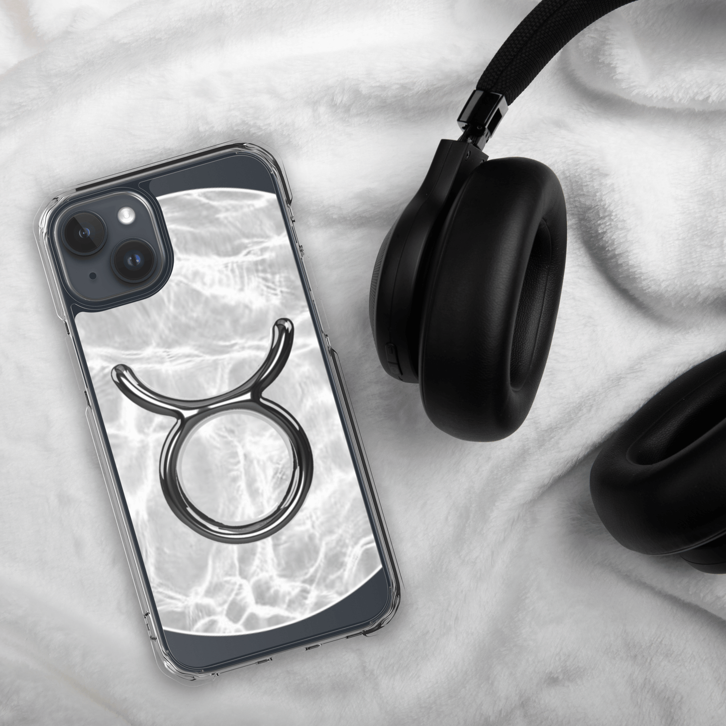 Zodiac Taurus Magsafe clear iPhone case with metallic design on marble background, stylishly displayed with headphones.