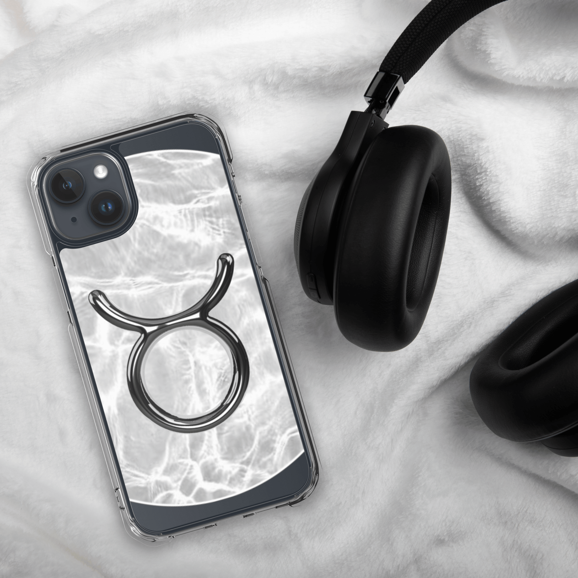 Zodiac Taurus Magsafe clear iPhone case with metallic design on marble background, stylishly displayed with headphones.