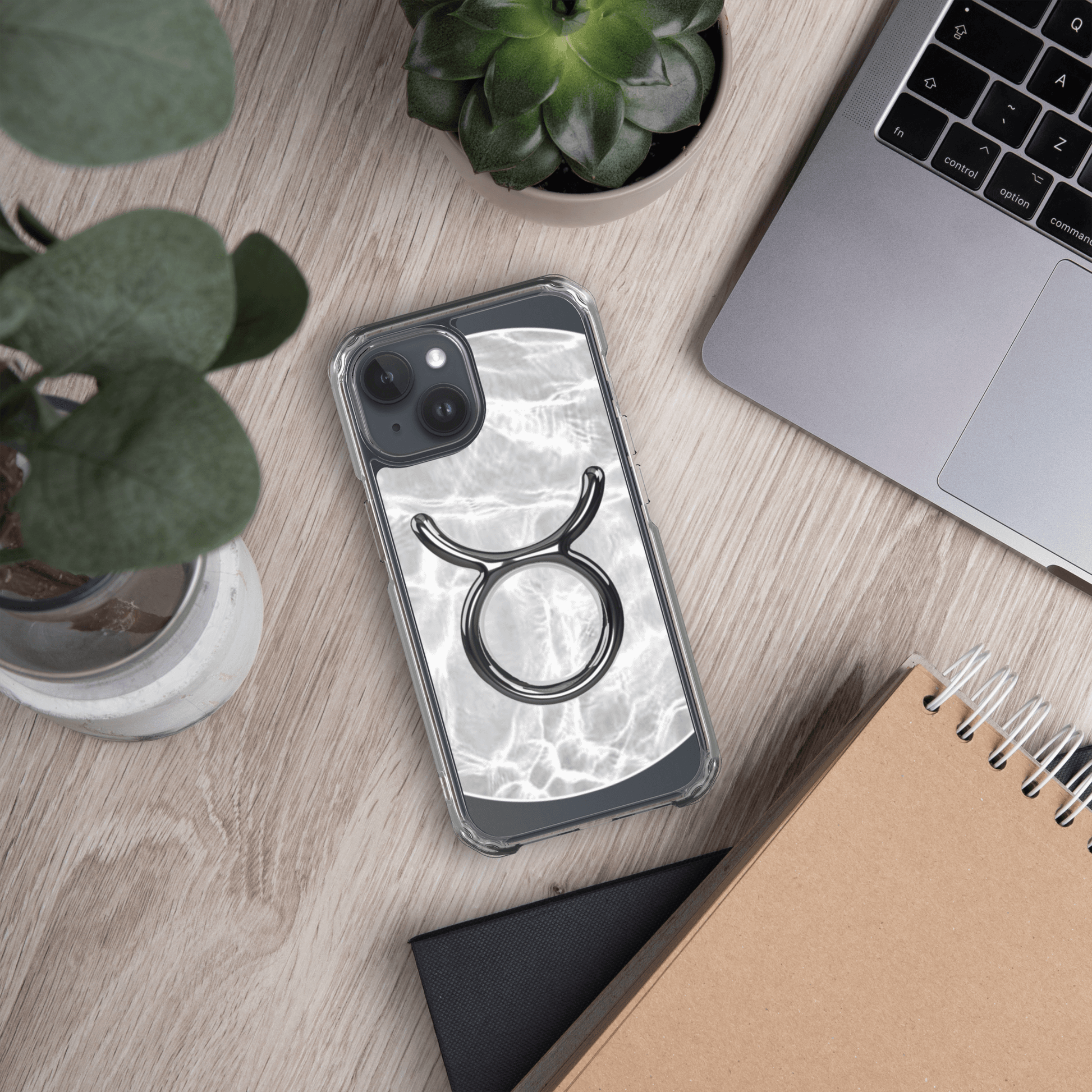 Zodiac Taurus Magsafe clear iPhone case with marble design on a desk with plants and a laptop.