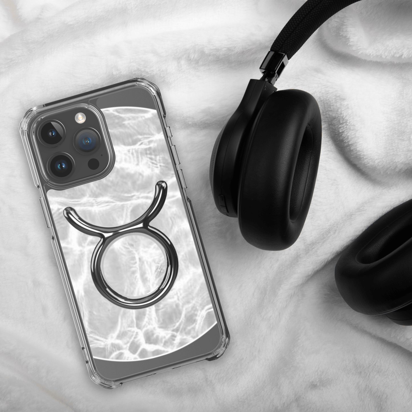 Zodiac Taurus MagSafe clear iPhone case with marble design, showcasing elegance and strength, next to black headphones.