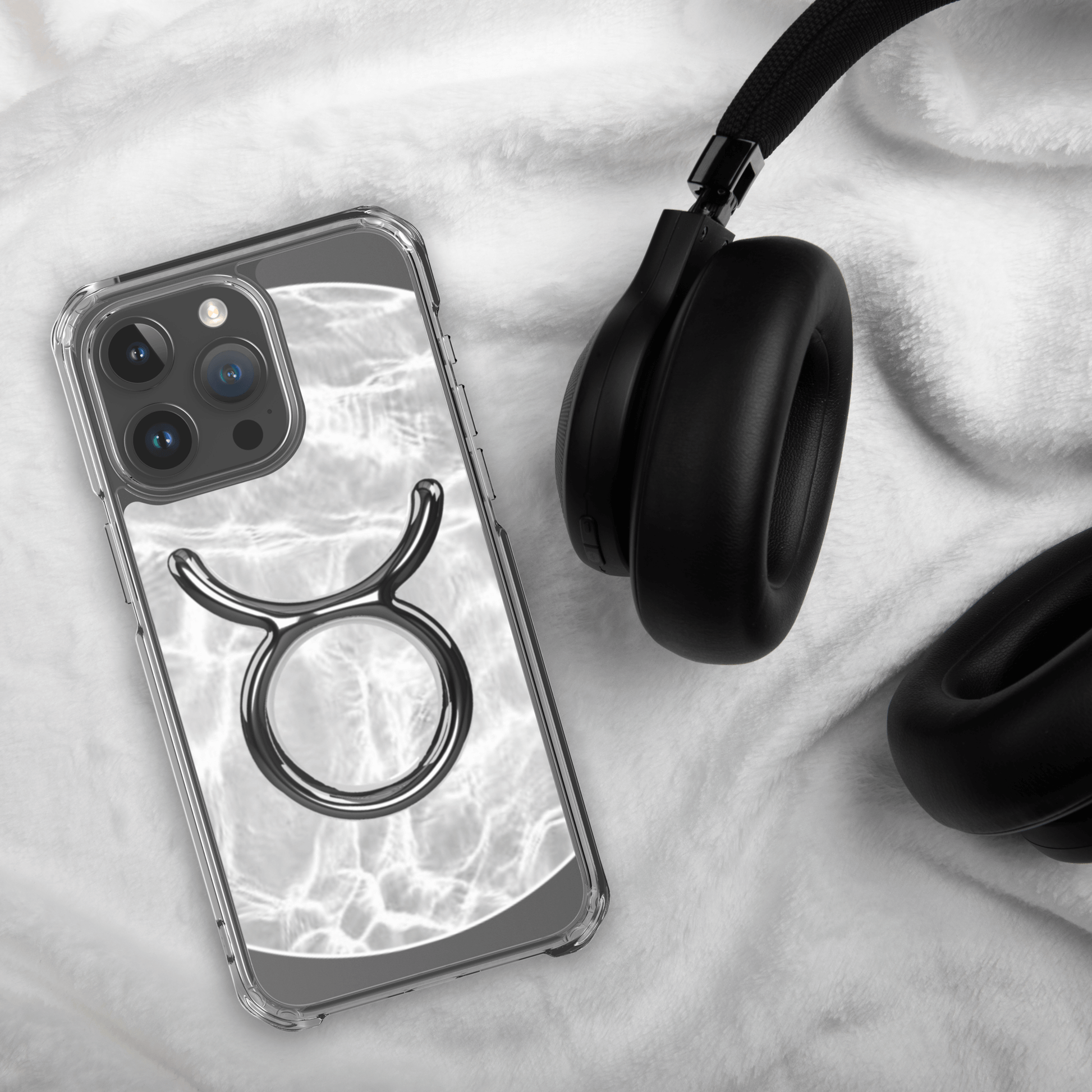 Zodiac Taurus MagSafe clear iPhone case with marble design, showcasing elegance and strength, next to black headphones.