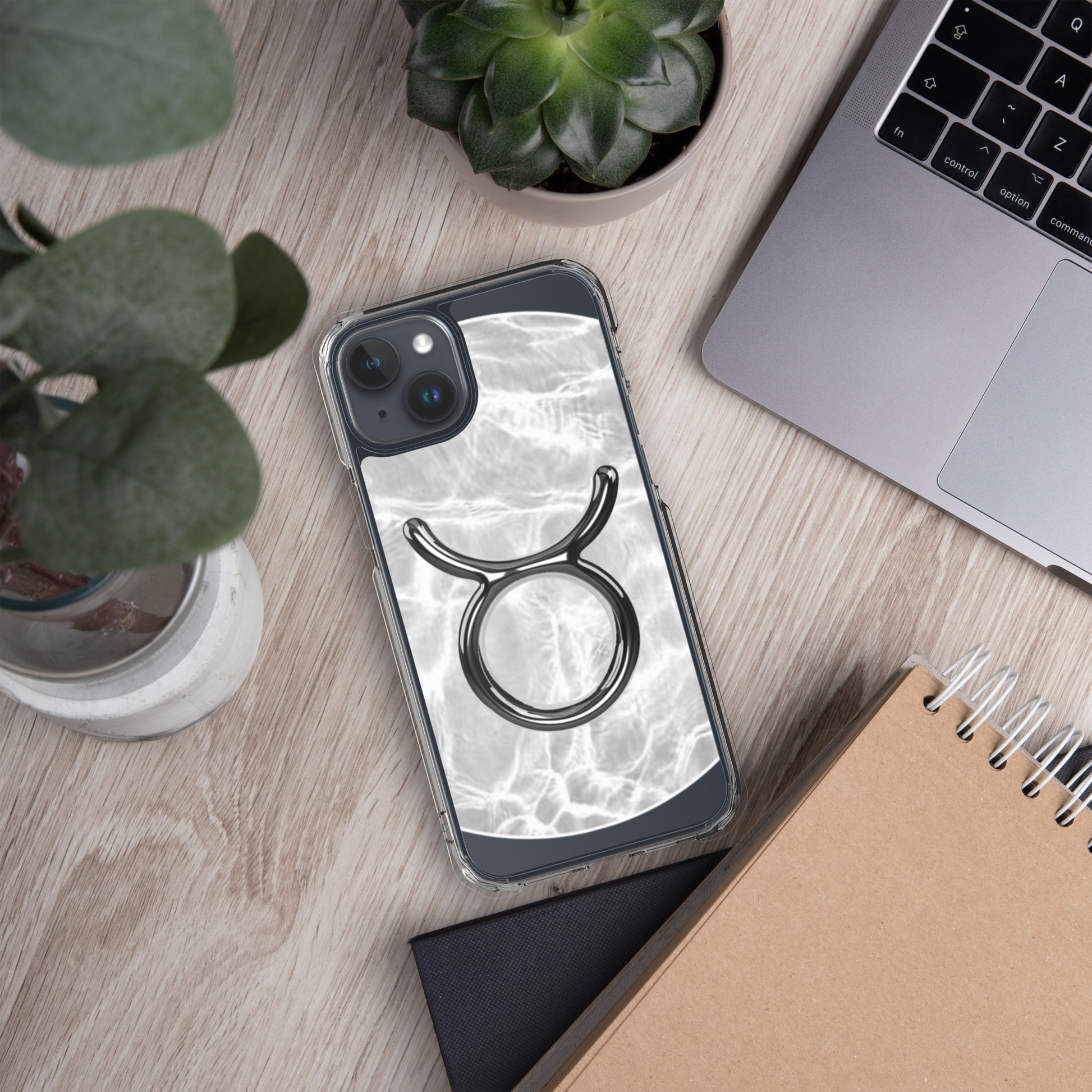 Zodiac Taurus MagSafe clear iPhone case with marble metallic design on a wooden desk.