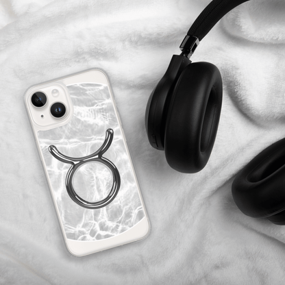 Zodiac Taurus Magsafe clear iPhone case with marble design beside black headphones on soft blanket.